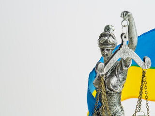 Sculpture of the goddess of justice - Themis on the background of the flag of Ukraine. Isolated on white background. There are no people in the photo. There is free space to insert.