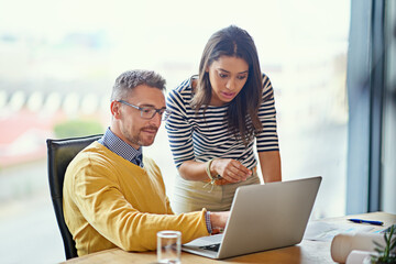 They are connected in more ways than one. Shot of coworkers working together on a laptop in an...