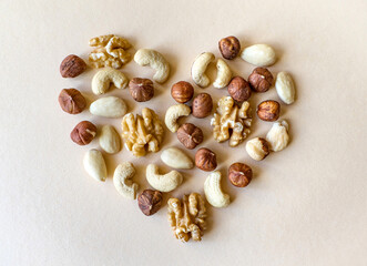 A variety of nuts shaped like a heart isolated on beige background