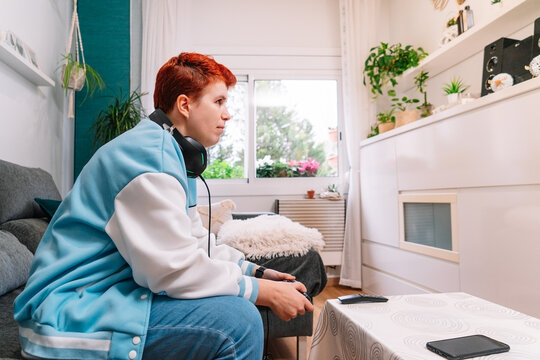 Non-binary person playing video games in the living room at home