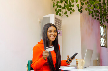 using bank card with ease beautiful young black woman holding mobile phone and credit card