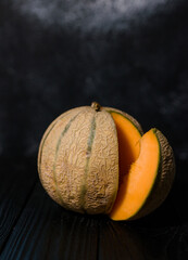 sweet melon on a dark background small delicious beautiful melon, both whole and in pieces and folded for eating