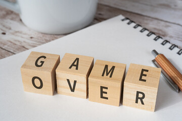 ゲームオーバーのイメージ｜「GAME OVER」と書かれた積み木と筆記用具とコーヒーカップ