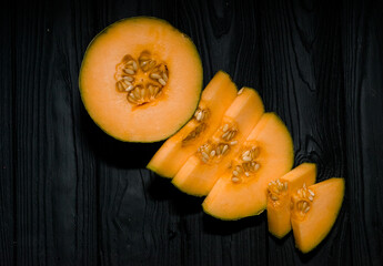 sweet melon on a dark background small delicious beautiful melon, both whole and in pieces and folded for eating