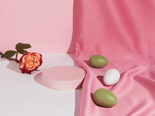 Pastel pink composition with satin curtain, rose flower and colorful Easter eggs. Suitable for Product Display and Business Concept. Modern aesthetic. Happy Easter holiday.