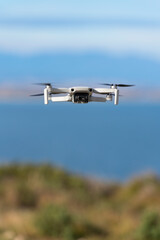 Small drone flying still with a defocused sea background