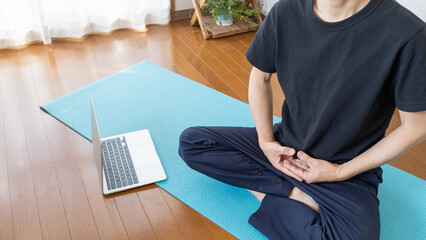家でPC動画を見ながら瞑想をする男性・法界定印ポーズ イメージ