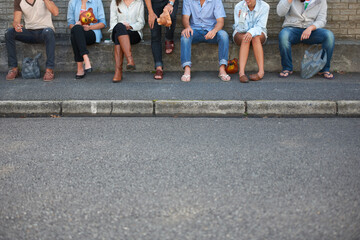 Hipsters in a row. Cropped view of young hipster friends seated outdoors.
