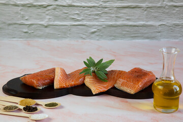 Fresh salmon fillets, garnished with spices, ready to eat, on a wooden plate