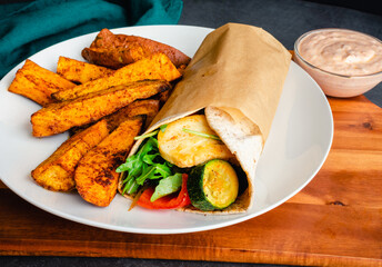 Roasted Vegetable and Halloumi Wrap Served with Sweet Potato Wedges: Vegetarian wrap with zucchini,...