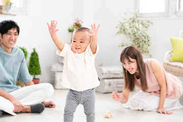 部屋で遊ぶ赤ちゃんとそれを見守る両親