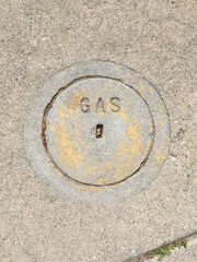 Close-up view of a small concrete cover plate for a gas valve on a city street sidewalk