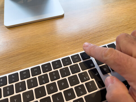Paris, France - Mar 18, 2022: Close-up male hand pressing fingerprint scanner on new Magic Keyboard with Touch ID and touch bar during the sales launch at the Apple Inc. flagship store