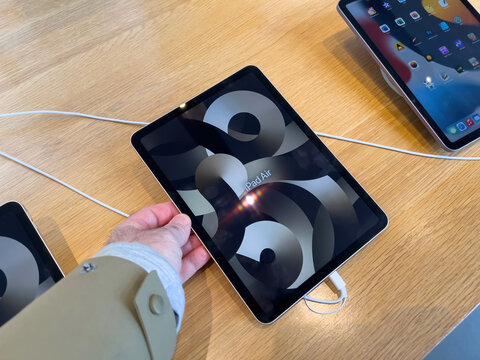 Paris, France - Mar 18, 2022: POV customer male hand with close-up of new iPad Air 5 tablet with with logotype during launch sales of tablet and Apple SE 3 smartphone, Mac Studio M1 Ultra