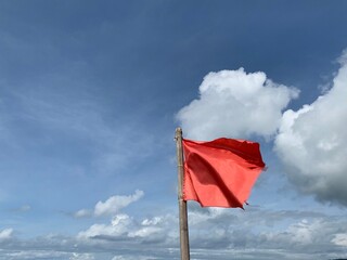 red flag on the beach with dramatic sky