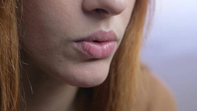 Close-up beautiful mouth, with bright pink lipstick, of young woman with long red hair who reads, talks, listens intently.