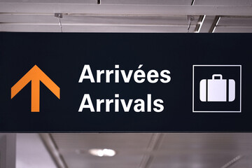 Canadian airport arrivals sign in bilingual English and French at Pearson international airport terminal hall.