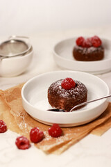 Chocolate lave cake on a white plate with raspberries, white marble table