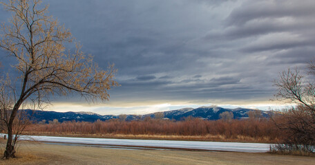 Missouri river frozen in Montana with cottonwood trees and mountains