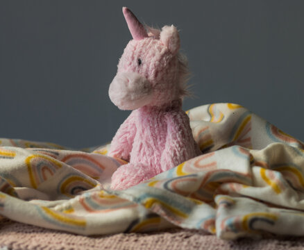 Stuffed pink unicorn on a rainbow blanket