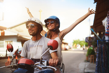 Simply enjoy the ride. Shot of young tourists enjoying a scooter ride around the city.