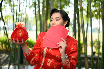 Asian pretty Chinese woman in cheongsam holding Red amulet bag and envelope fan