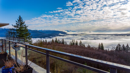 Dense cloud inversion over valley with alpine mountain backdrop as seen from a BC patio.