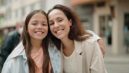 Mother and daughter smiling confident hugging each other at street