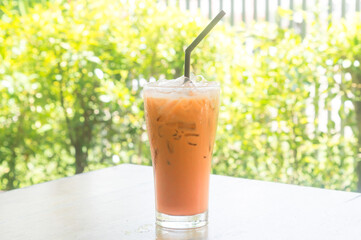 Iced orange Thai milk Tea in transparent glass with black straw served at coffee shop in upcountry