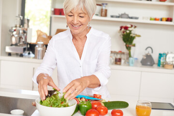 The secret to vitality is a healthy diet. Shot of a senior woman making a salad in her kitchen.