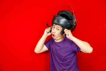 The Asian man who wore a helmet on his head had a shocked expression. red background photo studio.