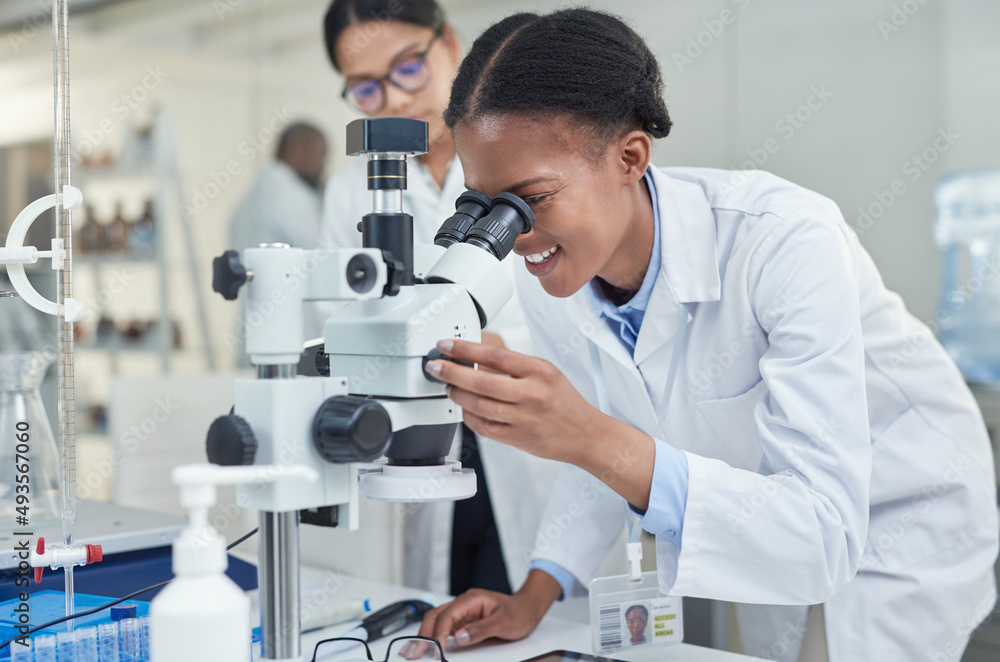 Poster science allows you to see a lot more. shot of a young scientist using a microscope in a lab.