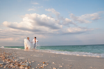Bride and groom running in sunshine on a beautiful tropical beach