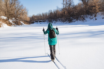 A person walks on skis in nature in the winter season. Training on cross-country skiing, traveling around the outskirts of his hometown, relaxing in the forest.