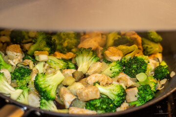 A delicious Chinese dish is fried chicken with broccoli in a wok. The process of cooking chicken with broccoli vegetables in a steel pan. Teriyaki chicken and broccoli in a cast-iron pan. 