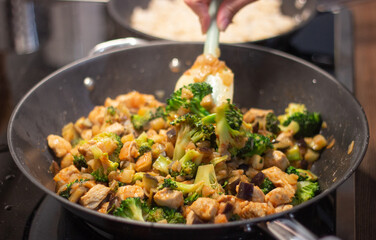 A delicious Chinese dish is fried chicken with broccoli in a wok. The process of cooking chicken with broccoli vegetables in a steel pan. Teriyaki chicken and broccoli in a cast-iron pan. 