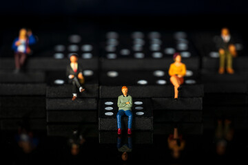 Obraz premium miniature people on dominoes Black background Macro