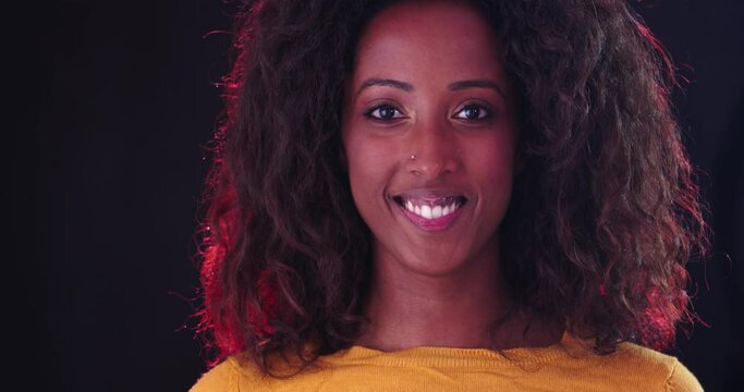 Portrait of attractive smiling african woman looking at camera isolated on black