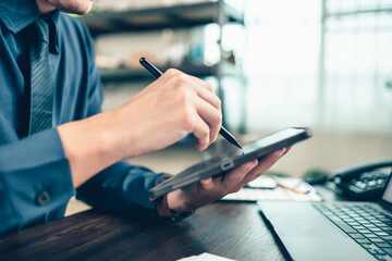 Business hand hold stylus pen touch screen digital tablet with business diagram on the table workspace.