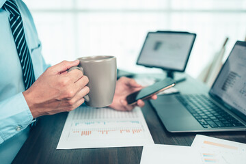 Businessman drink coffee and use cell phone and working on office desk and analyzing new project of accounting finance. Investment, Financial advisor and accounting concept.