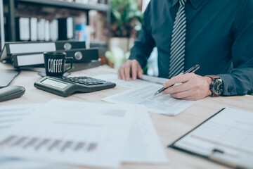 Accountant writing, checking and working on company data, document, report and calculator to calculate  on desk office. Accounting business concept.