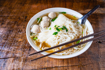.Noodle and meatballs in a bowl on a wooden table