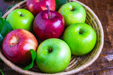 .Green apple and red apple in a basket on a wooden background