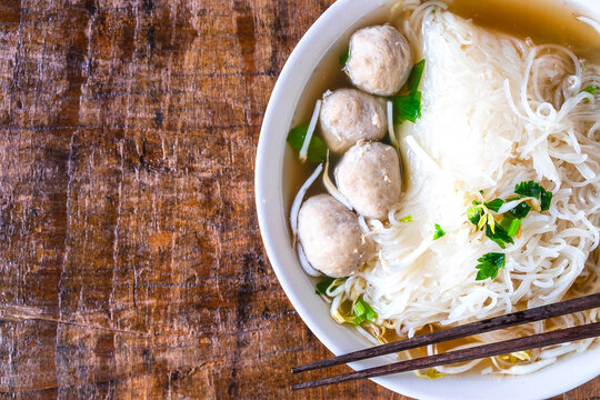 .Noodle and meatballs in a bowl on a wooden table