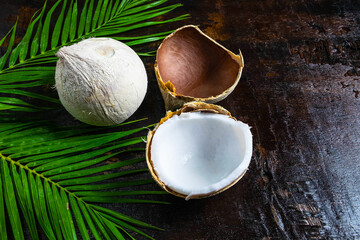 Fototapeta na wymiar half of coconut with leaves on wooden background