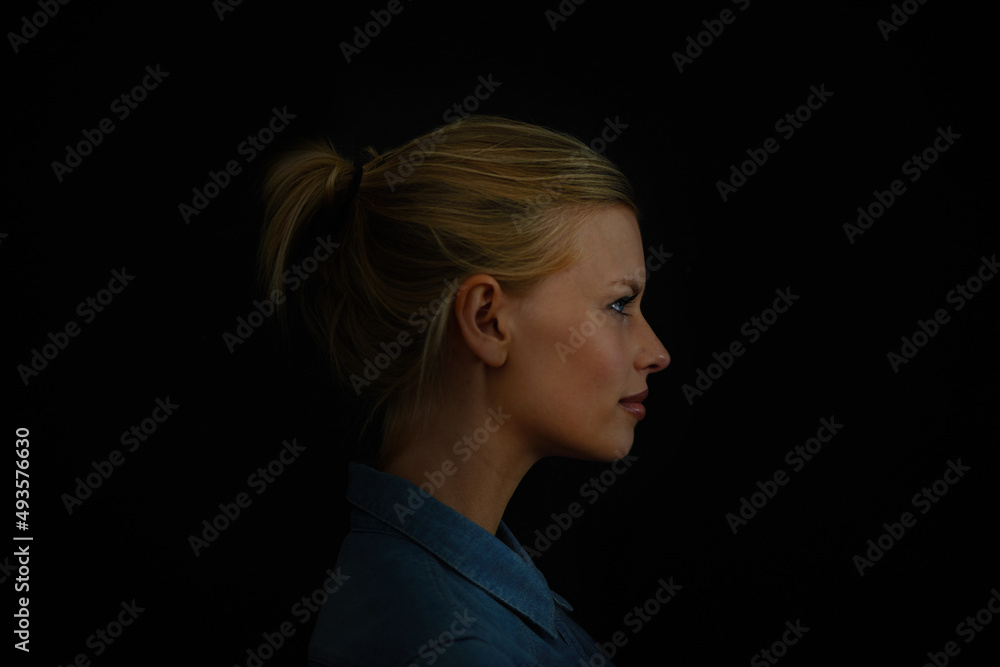 Wall mural brodd. a young woman in a denim shirt against a dark background.