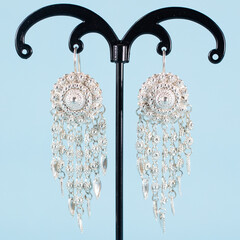 A pair of silver earrings on blue background