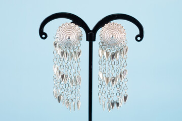 A pair of silver earrings on blue background