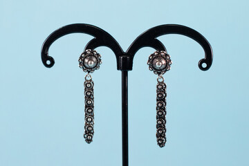 A pair of silver earrings on blue background