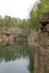 Fototapeta na wymiar Old rock quarry filled with water in summer at Vehmaa, Finland.